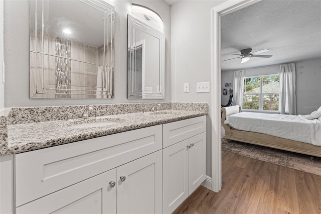 bathroom with ceiling fan, walk in shower, hardwood / wood-style floors, a textured ceiling, and vanity