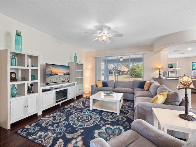 living room featuring ceiling fan, dark hardwood / wood-style flooring, and a textured ceiling