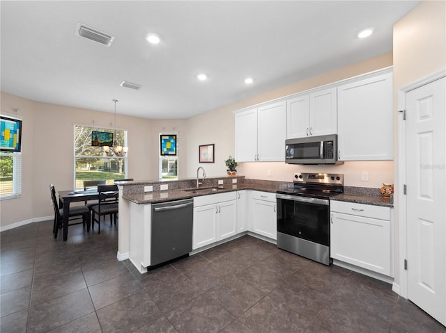 kitchen featuring sink, decorative light fixtures, appliances with stainless steel finishes, kitchen peninsula, and white cabinets