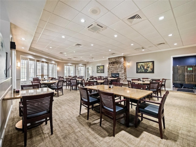 carpeted dining area with ornamental molding and a fireplace