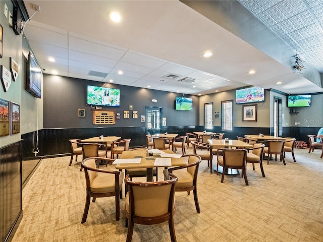 dining space featuring light carpet and a drop ceiling