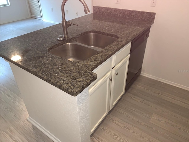 kitchen with light wood-type flooring, white cabinetry, sink, and dark stone counters