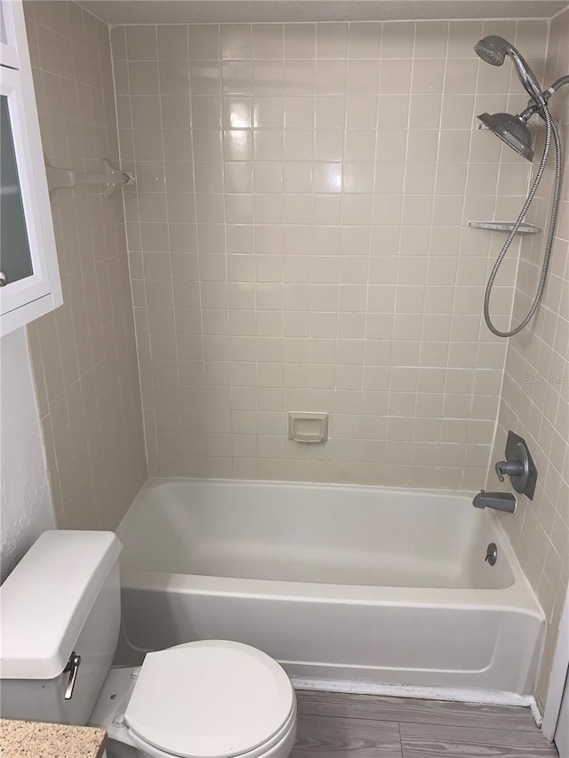 bathroom with hardwood / wood-style flooring, tiled shower / bath combo, and toilet