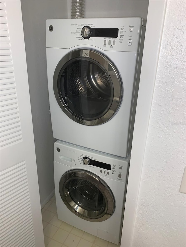 laundry room with stacked washing maching and dryer and light tile patterned floors