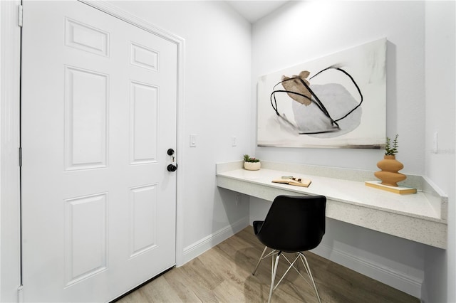 home office featuring built in desk and light hardwood / wood-style flooring