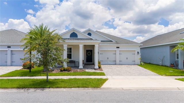 view of front of property featuring covered porch, a garage, and a front lawn