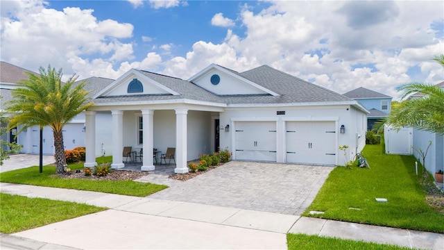 view of front of property featuring covered porch, a front yard, and a garage