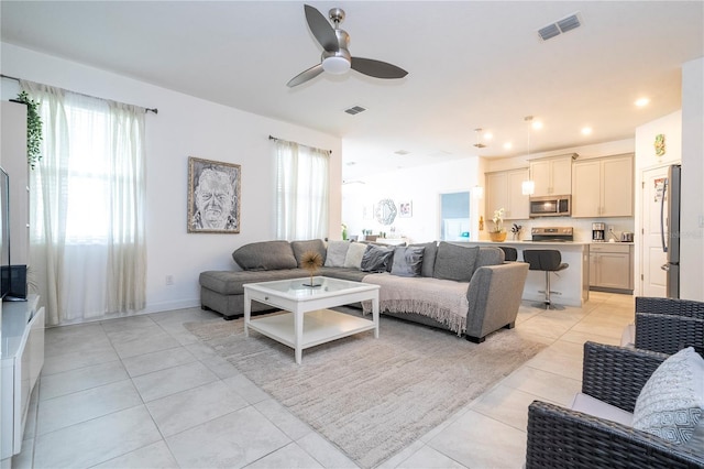 living room with ceiling fan, light tile patterned flooring, and a healthy amount of sunlight