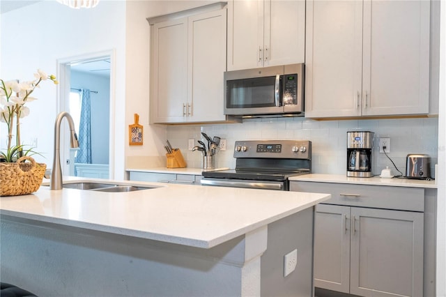 kitchen featuring decorative backsplash, appliances with stainless steel finishes, gray cabinets, and sink