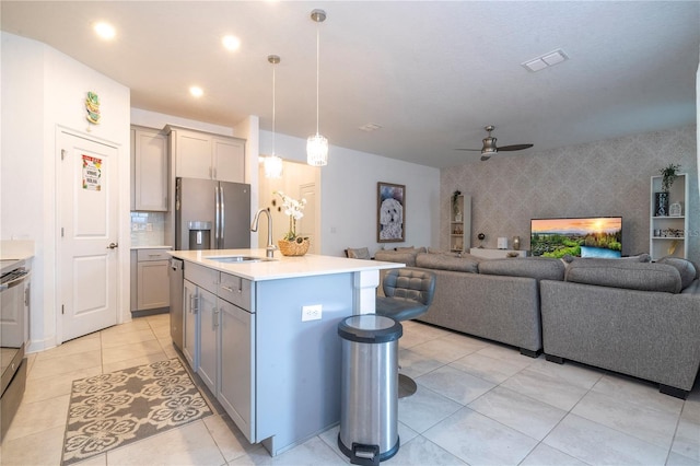 kitchen with pendant lighting, a kitchen island with sink, sink, ceiling fan, and stainless steel appliances