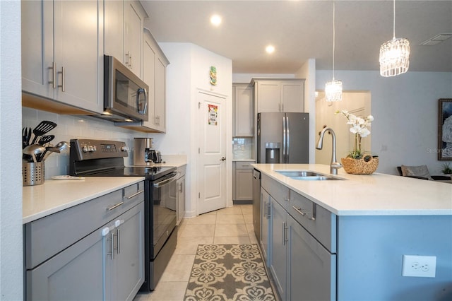 kitchen featuring sink, decorative backsplash, light tile patterned floors, appliances with stainless steel finishes, and decorative light fixtures