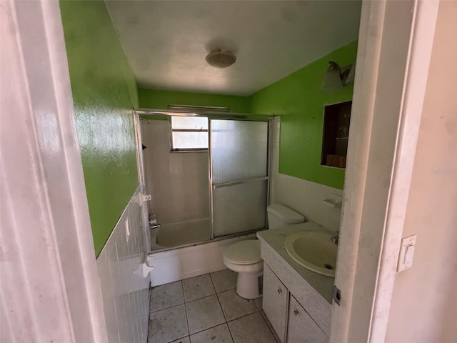 full bathroom featuring combined bath / shower with glass door, vanity, toilet, and tile patterned flooring