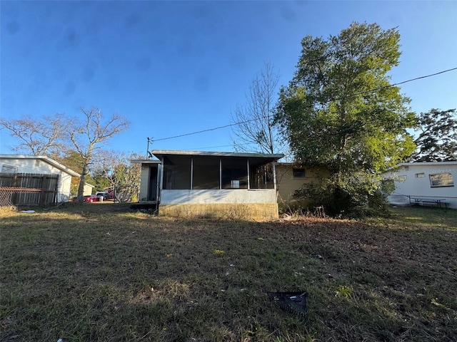 rear view of house with a sunroom and a yard