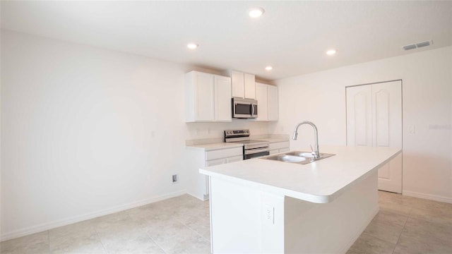 kitchen with sink, stainless steel appliances, light tile patterned floors, a kitchen island with sink, and white cabinets