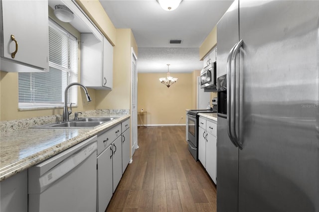 kitchen featuring sink, stainless steel appliances, white cabinetry, and decorative light fixtures