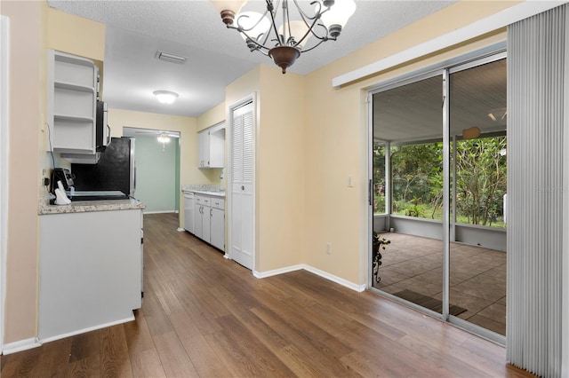 kitchen with decorative light fixtures, white cabinets, an inviting chandelier, and hardwood / wood-style floors