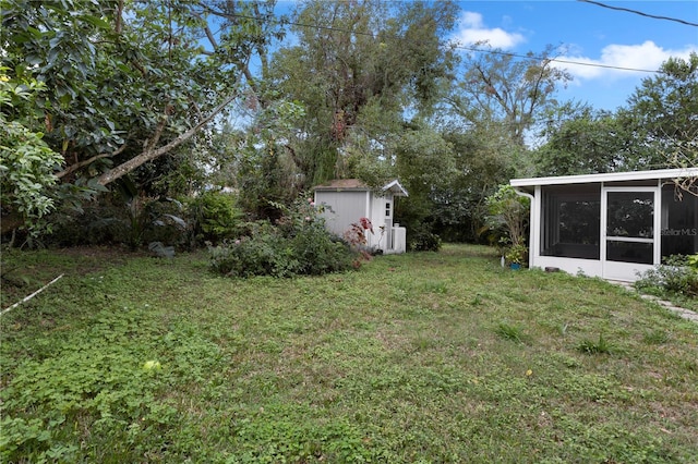 view of yard featuring a sunroom and a storage shed