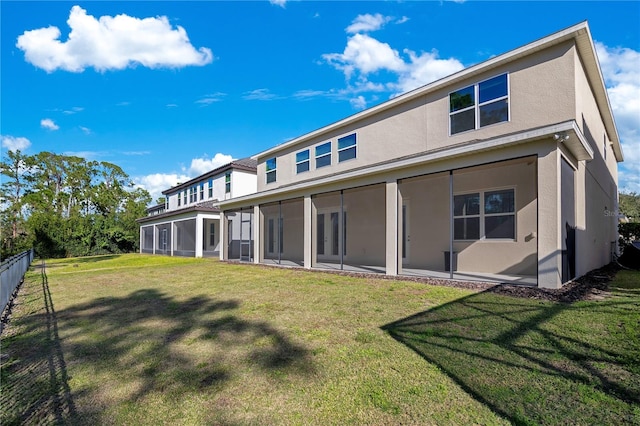 rear view of property featuring a sunroom and a lawn