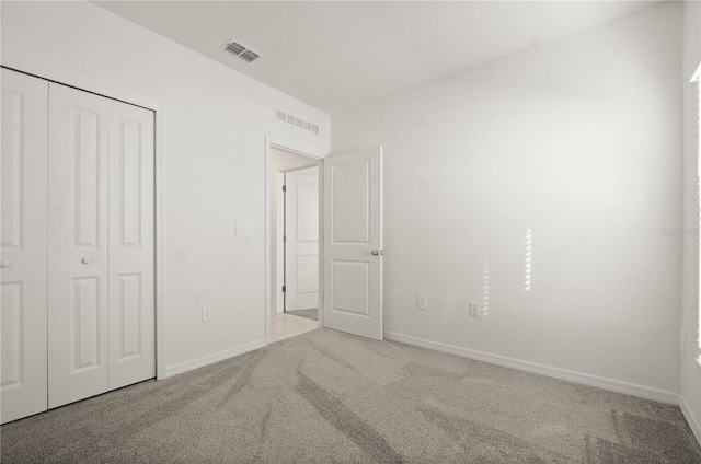 unfurnished bedroom featuring light carpet and a closet