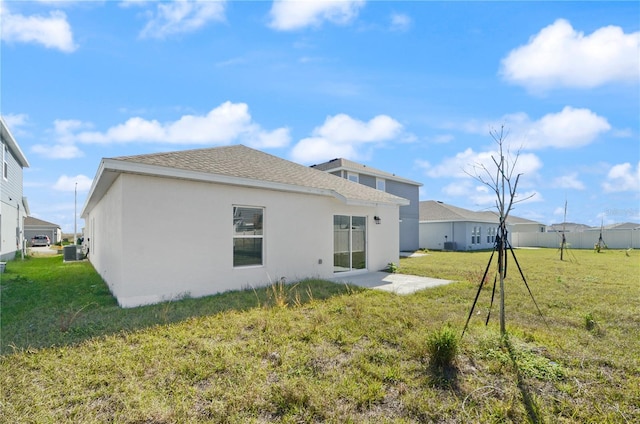 back of house with central AC unit and a yard