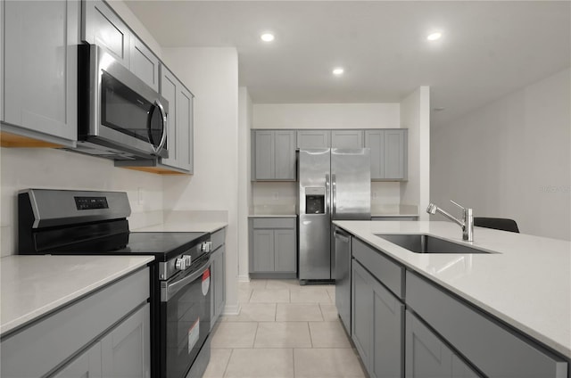 kitchen with light tile patterned floors, appliances with stainless steel finishes, sink, and gray cabinetry