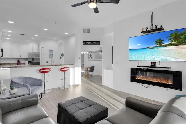 living room featuring light hardwood / wood-style floors, ceiling fan, and sink