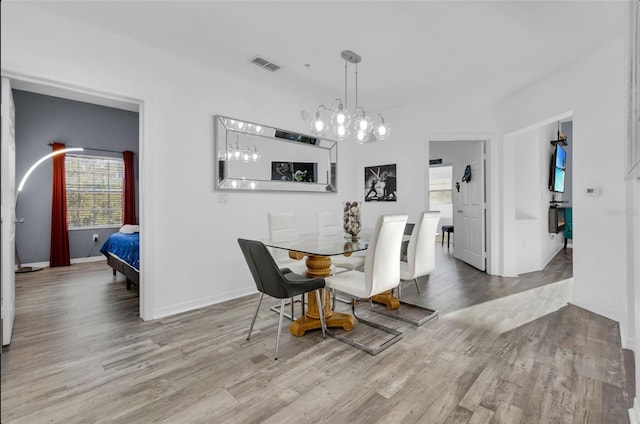 dining area with light hardwood / wood-style floors and an inviting chandelier