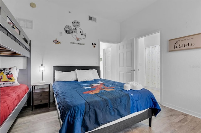 bedroom with light wood-type flooring and connected bathroom