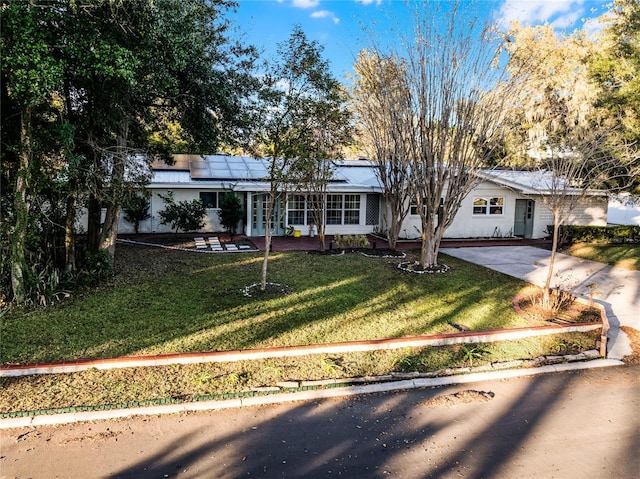 ranch-style home featuring a front lawn and solar panels