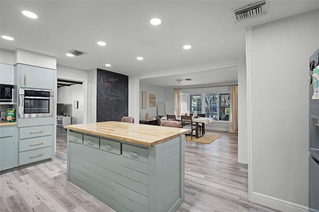 kitchen with wooden counters, light hardwood / wood-style floors, a kitchen island, and stainless steel oven