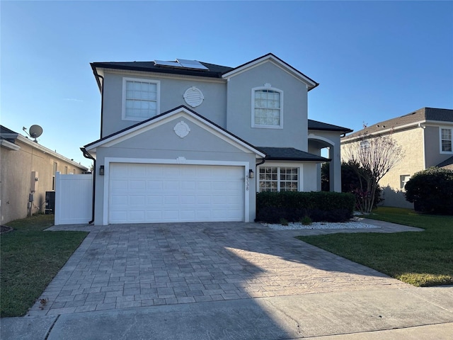 front of property with solar panels, cooling unit, a garage, and a front yard