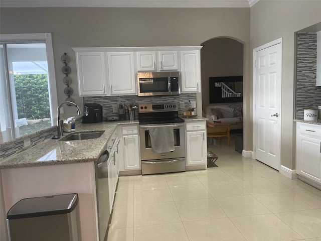 kitchen with appliances with stainless steel finishes, tasteful backsplash, sink, light tile patterned floors, and white cabinetry