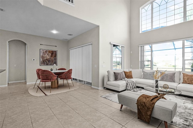 tiled living room featuring a towering ceiling