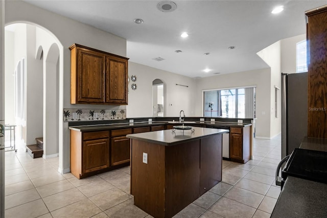 1108 Darnaby Way, Orlando, FL 32824 - kitchen featuring a peninsula, dark countertops, arched walkways, a sink, and stainless steel appliances