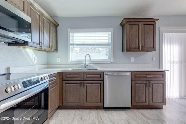 kitchen with stainless steel appliances, a sink, and light countertops