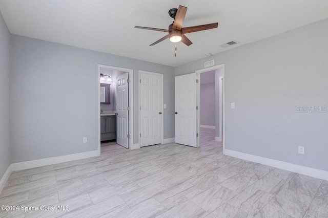 unfurnished bedroom with a ceiling fan, ensuite bath, visible vents, and baseboards