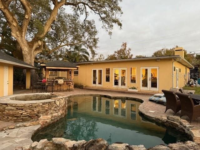 view of swimming pool with an in ground hot tub, french doors, exterior bar, and a patio