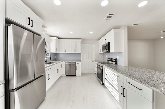 kitchen featuring light stone countertops, sink, white cabinets, and appliances with stainless steel finishes