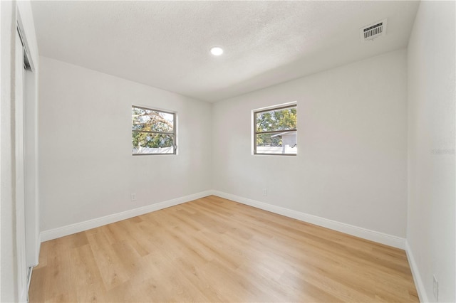 empty room with a textured ceiling and light wood-type flooring