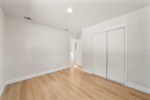 unfurnished bedroom with light hardwood / wood-style flooring and a closet