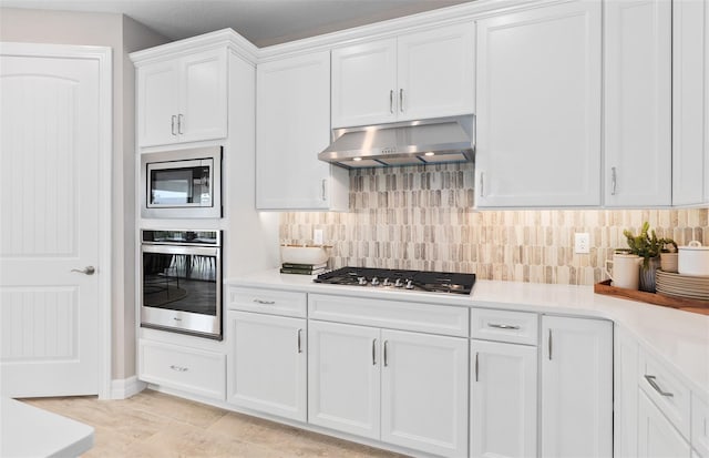 kitchen with ventilation hood, decorative backsplash, white cabinetry, and stainless steel appliances