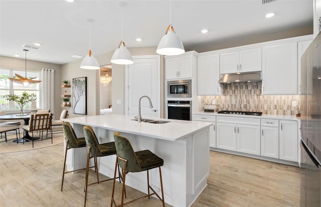 kitchen with sink, a center island with sink, pendant lighting, and appliances with stainless steel finishes