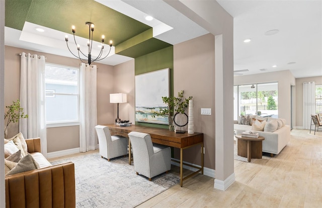 office area featuring a notable chandelier, a raised ceiling, and light wood-type flooring