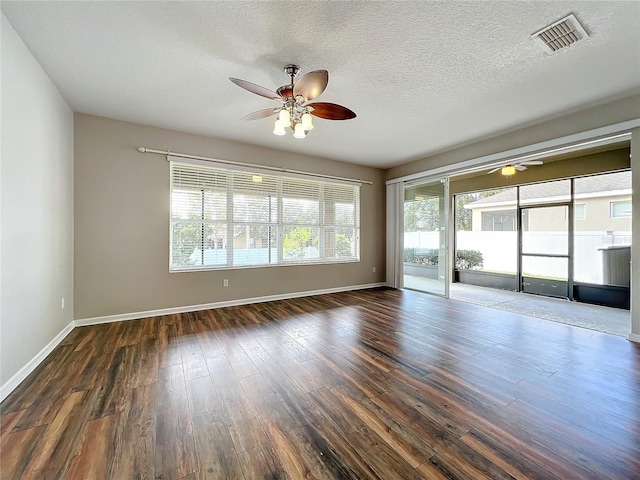 empty room with ceiling fan, dark wood-type flooring, and a textured ceiling