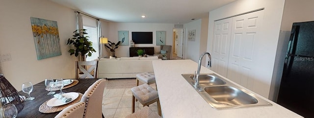 kitchen with black fridge, light tile patterned floors, and sink