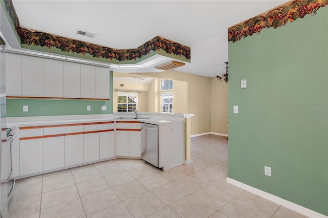 kitchen with kitchen peninsula, stainless steel dishwasher, sink, a notable chandelier, and white cabinetry