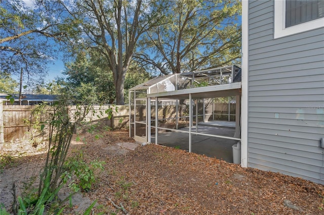 view of yard with glass enclosure and a patio