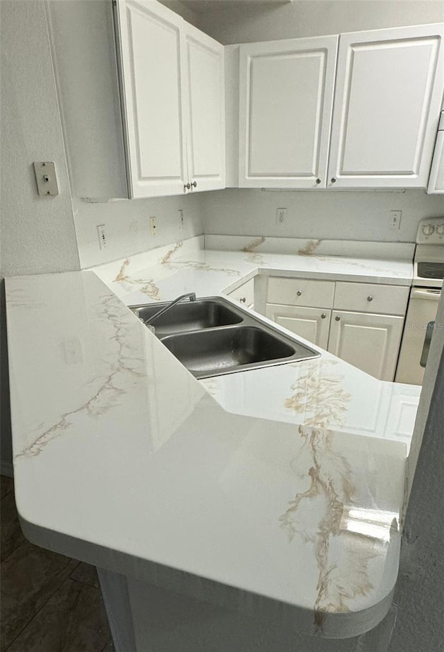 kitchen featuring white cabinets, stove, and sink