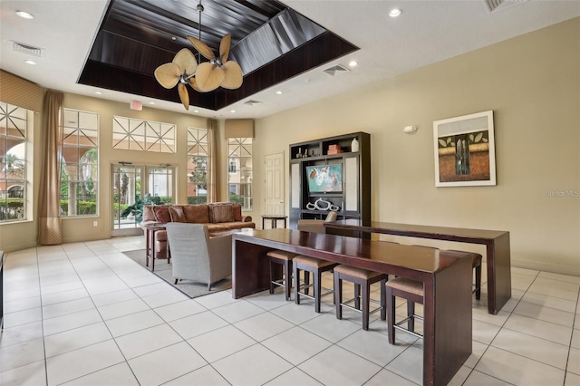 tiled living room with a raised ceiling and ceiling fan