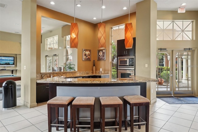 kitchen with a breakfast bar, stainless steel microwave, kitchen peninsula, and pool table